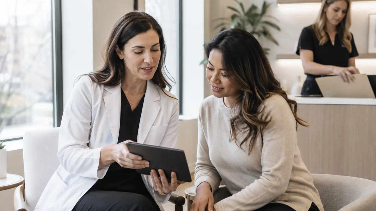 A dermatologist and patient review care information together on a tablet during a consultation